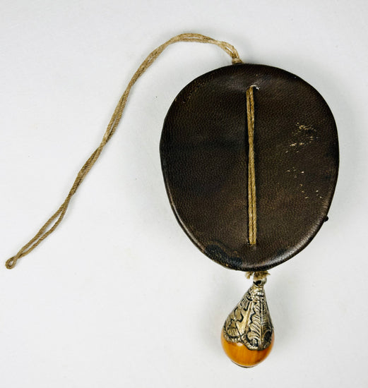 Tibetan devotional mask ornament with leather mounting and drop pendant