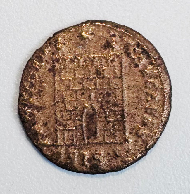 Close-up of a Late Roman copper-alloy camp-gate type coin, likely Constantinian era, with fortified gateway reverse.