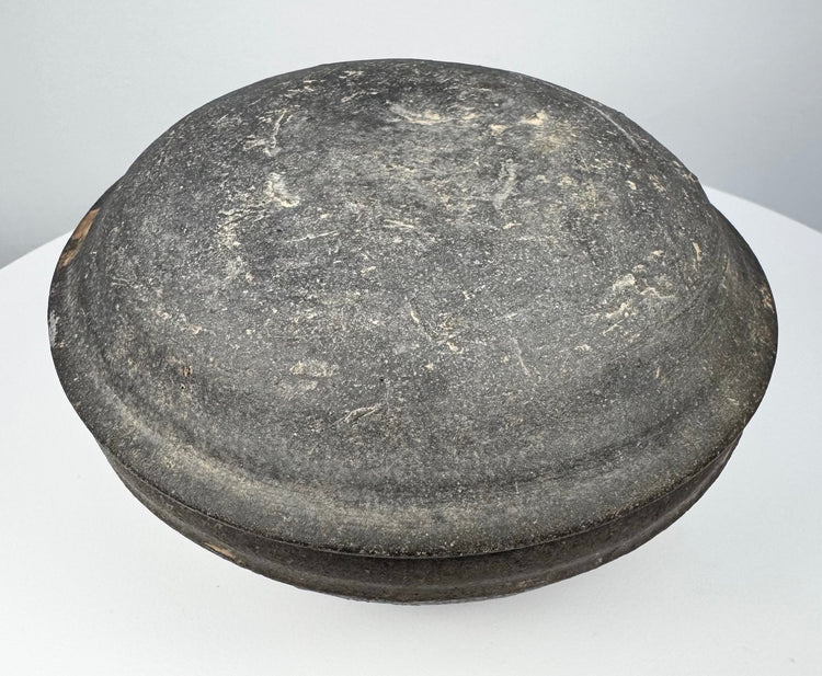 Ancient Chinese gray pottery covered box viewed from above, highlighting the broad domed cover and dark aged surface.