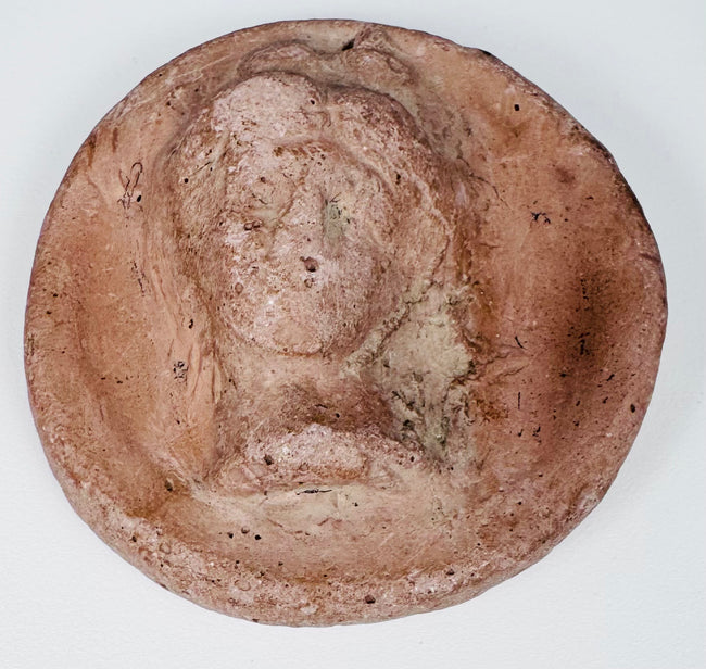 Greek Hellenistic female bust appliqué with centrally arranged hair, drapery, and circular relief format.