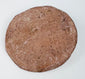 Reverse of a Hellenistic Greek terracotta female bust medallion showing the plain flattened back, aged pinkish-buff surface, mineral deposits, and edge wear.
