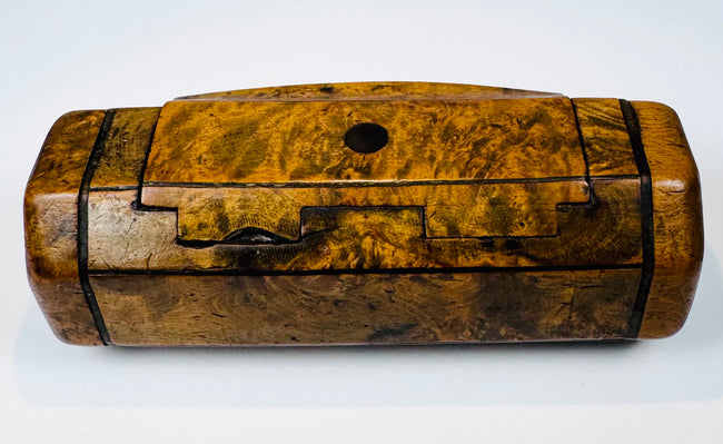 British 19th-century wooden snuff box with figured walnut grain, hinged top, and small circular dark inset.