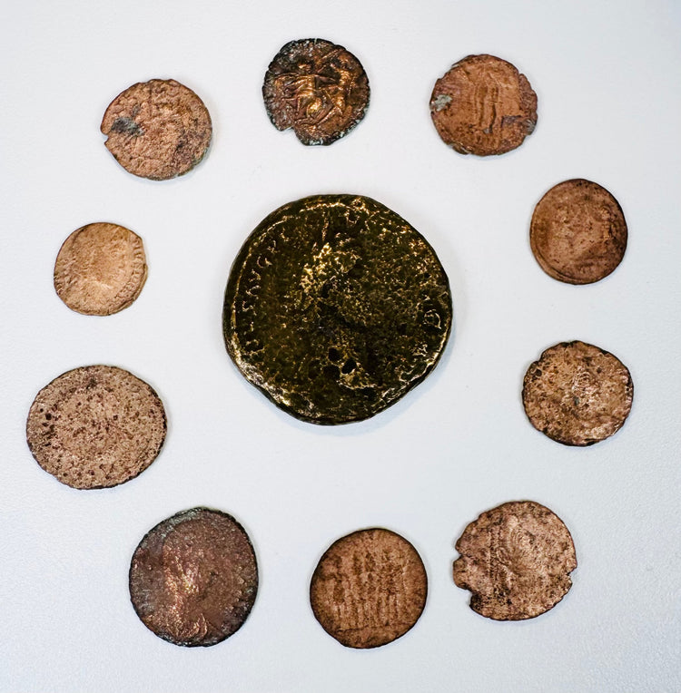Ten Late Roman bronze coins arranged around a large central imperial coin, showing varied flan sizes, wear, and historic patination.