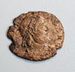 Ancient Late Roman bronze coin with right-facing emperor portrait, irregular flan, partial legend, and reddish-brown patina.