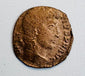 Ancient Roman bronze coin with right-facing imperial bust, surviving Latin legend, and heavily worn reddish-brown surface.