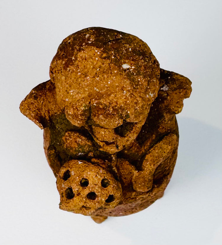 Detail of ancient Maya terracotta rattle with recessed eyes, projecting nose, and textured coiffure