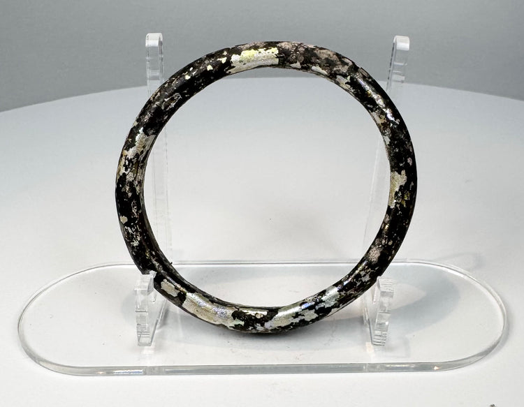 Side view of ancient Roman glass bracelet with thick rounded hoop and mottled mineral deposits