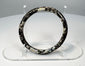 Side view of ancient Roman glass bracelet with thick rounded hoop and mottled mineral deposits