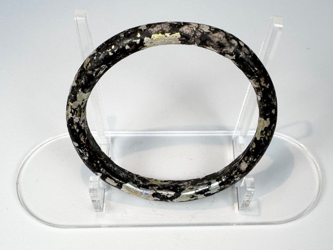 Close view of Roman glass bangle with pitting, exfoliation, and iridescent archaeological surface
