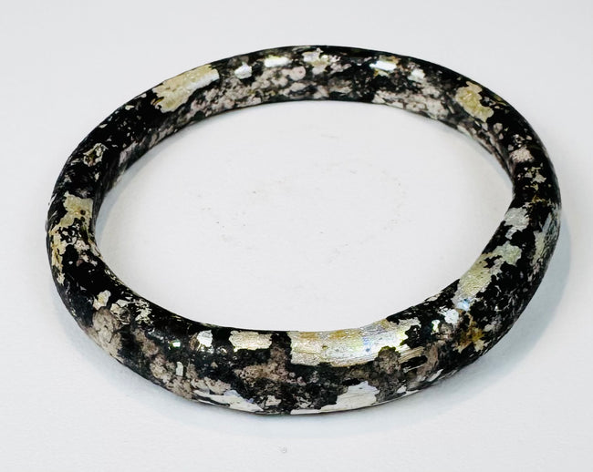 Ancient Roman dark glass bracelet with age-related pitting, dulling, and burial encrustation