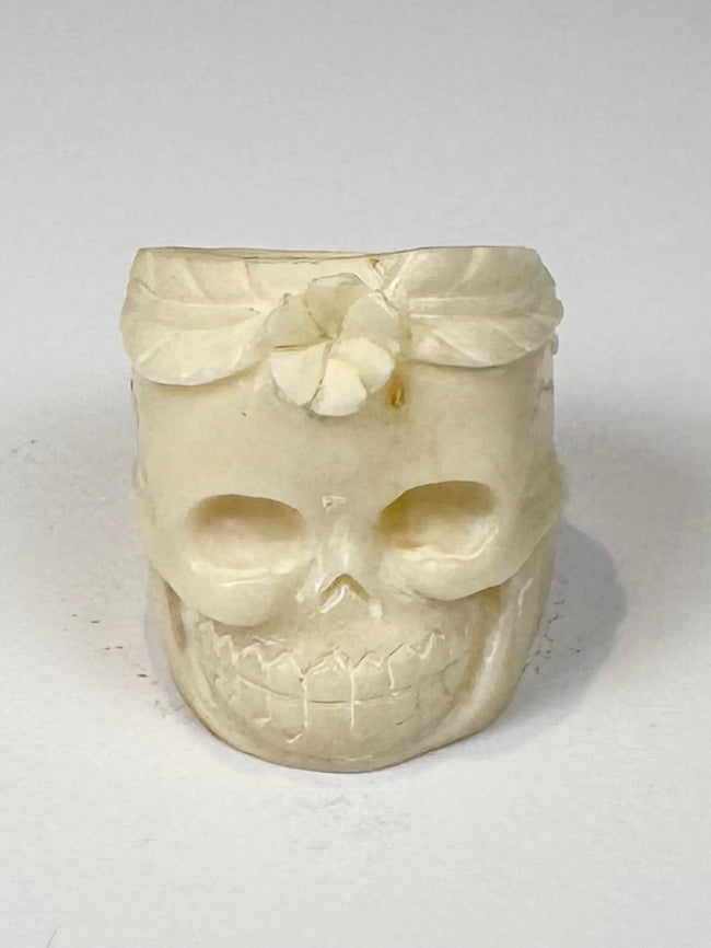 Carved camel bone jewelry ring with skull face, flower motif, and natural bone texture