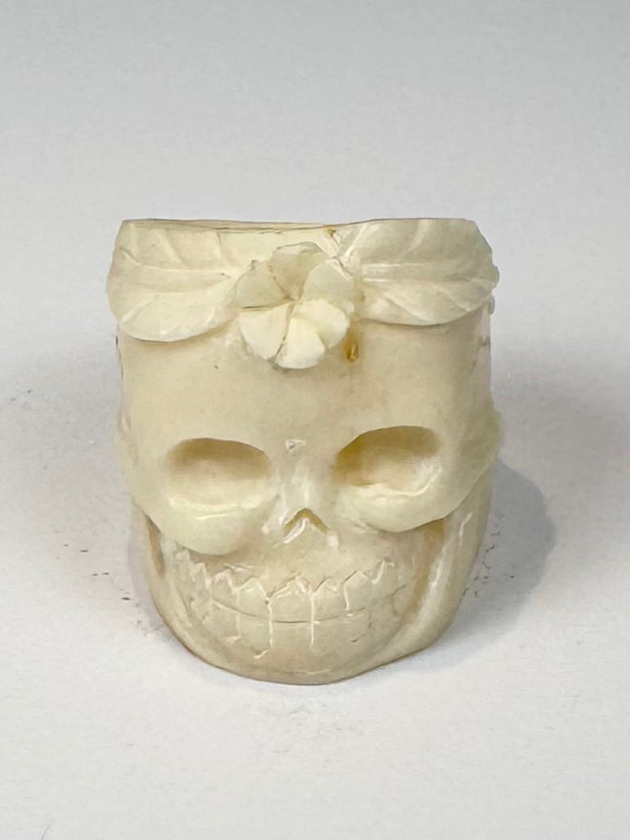 Carved camel bone jewelry ring with skull face, flower motif, and natural bone texture