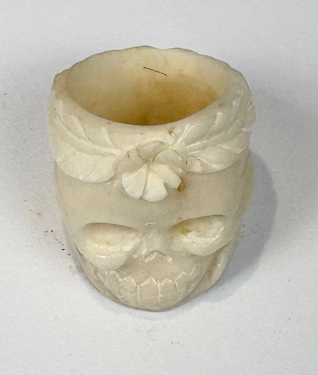 Front view of hand-carved skull ring with recessed eyes, nasal cavity, and floral crown