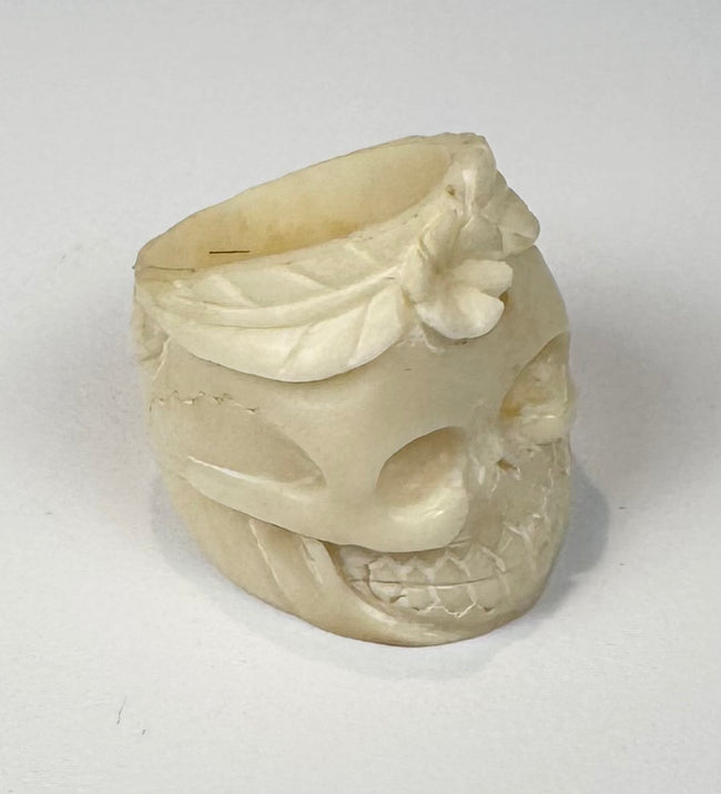 Antique-style camel bone ring carved as a human skull with flower motif