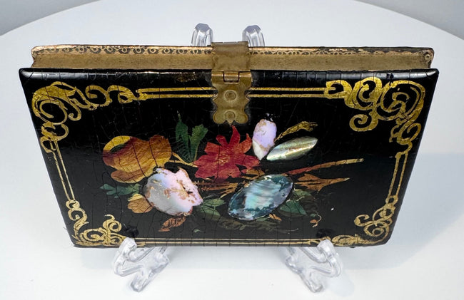 Black lacquer Victorian calling card case with floral ornament, gilt scrolling border, and central brass clasp