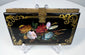 Black lacquer Victorian calling card case with floral ornament, gilt scrolling border, and central brass clasp