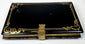 Reverse of Victorian black lacquer calling card case with gilt scrollwork border and brass clasp
