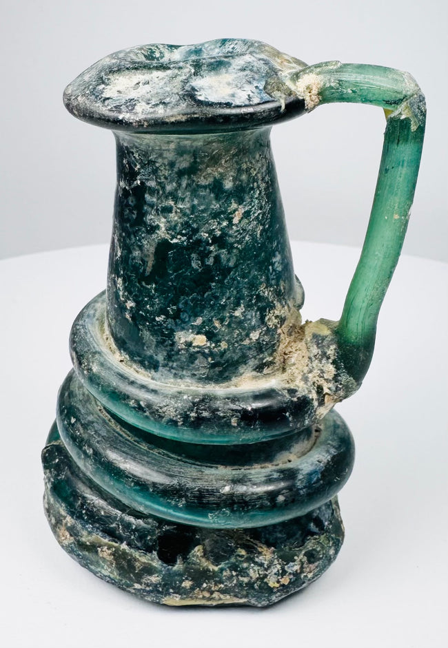 Late Roman glass jug highlighting iridescent weathering, mineral accretions, and hand-blown construction