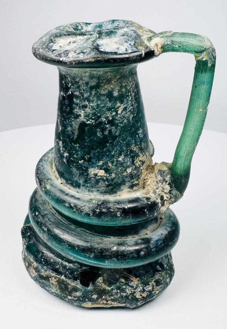 Late Roman glass jug highlighting iridescent weathering, mineral accretions, and hand-blown construction