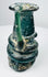 Late Roman green glass vessel showing applied handle, rounded body, and heavy burial deposits