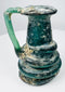 Ancient Roman green glass jug with flared rim, applied handle, and natural mineral encrustation