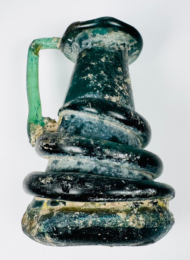 Ancient Roman glass jug with sculptural coiled glass trails and weathered archaeological surface