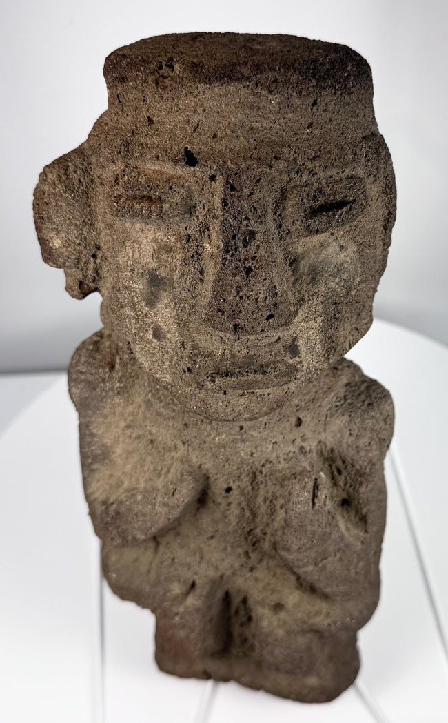 Ancient Mesoamerican carved stone figure showing weathering, mineral deposits, and surface patina