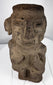 Ancient Mesoamerican carved stone figure showing weathering, mineral deposits, and surface patina