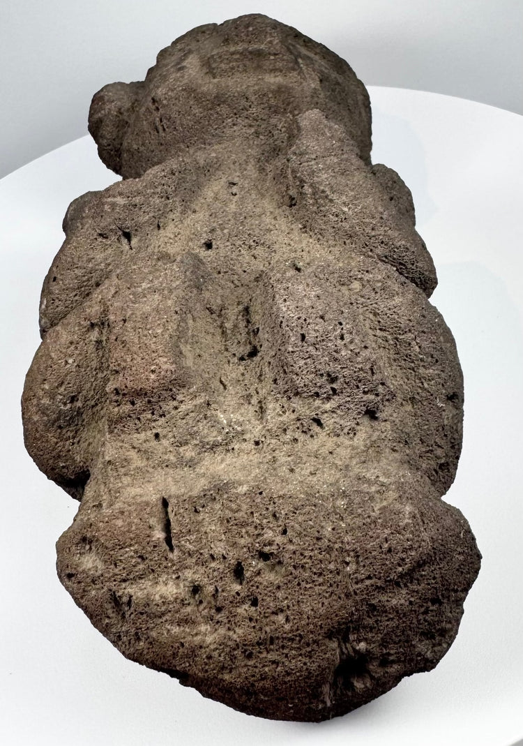 Pre-Columbian volcanic stone effigy with stylized face, folded arms, and seated posture