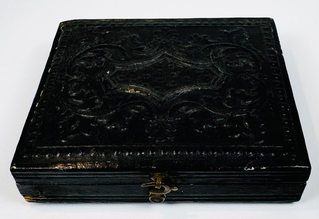 Closed mid-19th-century cased photograph with molded dark exterior, ornamental design, and metal clasp