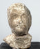 Ancient mold-made Greek terracotta bust with elongated face, recessed eyes, and projecting nose