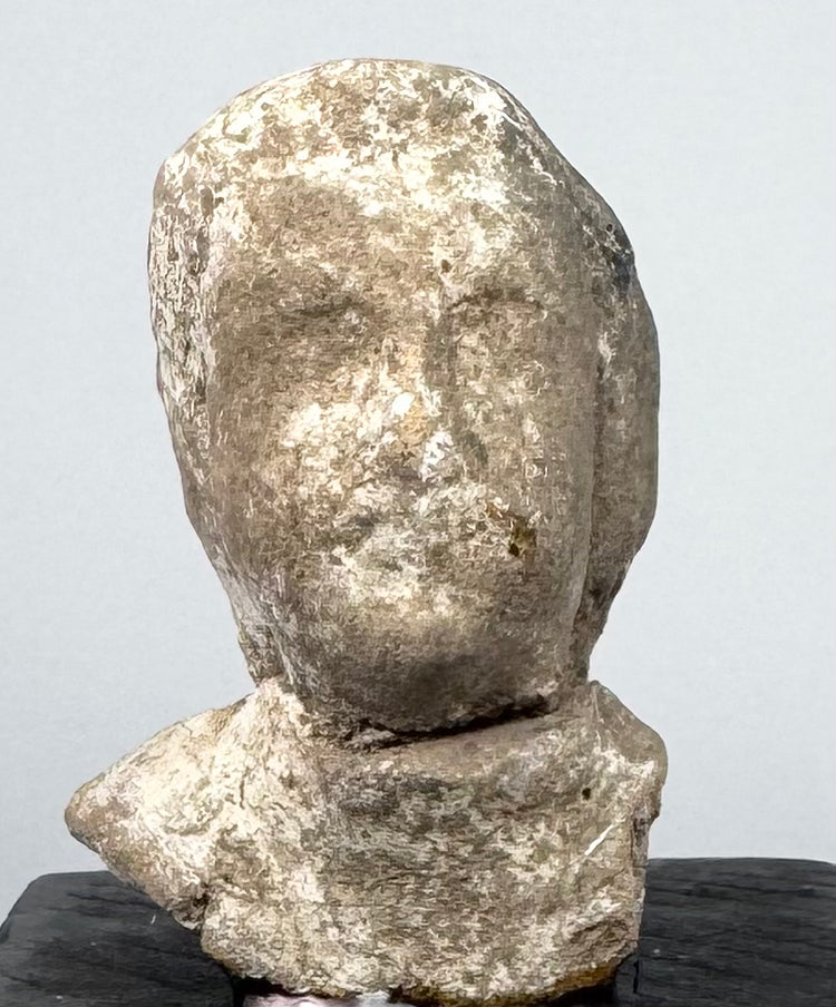 Ancient mold-made Greek terracotta bust with elongated face, recessed eyes, and projecting nose