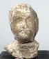 Ancient mold-made Greek terracotta bust with elongated face, recessed eyes, and projecting nose