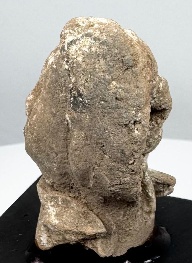 Greek terracotta protome showing heavily weathered facial features and surviving pale surface deposits