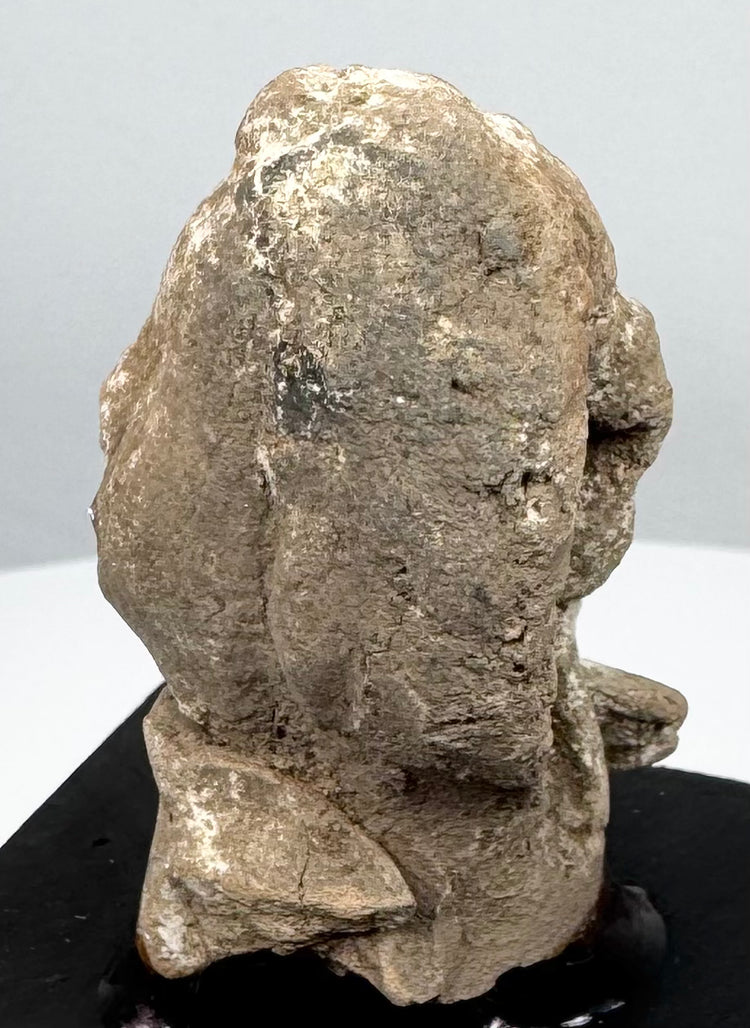 Greek terracotta protome showing heavily weathered facial features and surviving pale surface deposits