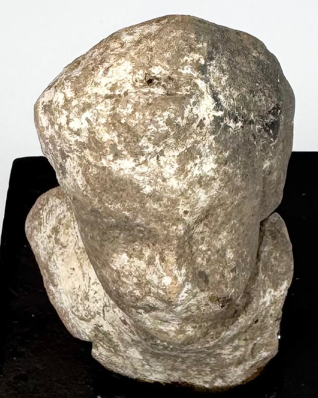 Ancient Greek terracotta protome showing weathered facial features, rounded head, broad shoulders, and pale archaeological surface deposits.