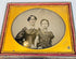 Victorian ambrotype of a woman and child seated together within an ornate gilt-brass oval presentation mat