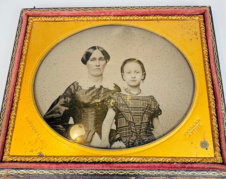 Victorian ambrotype of a woman and child seated together within an ornate gilt-brass oval presentation mat