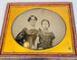 Victorian ambrotype of a woman and child seated together within an ornate gilt-brass oval presentation mat