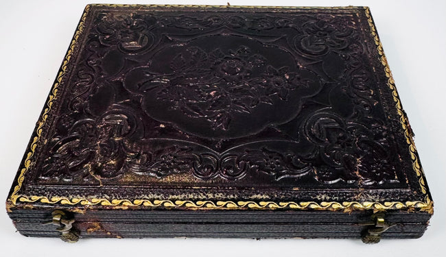 Antique photographic case with ornate embossed exterior, gilt border detailing, and metal closure hardware