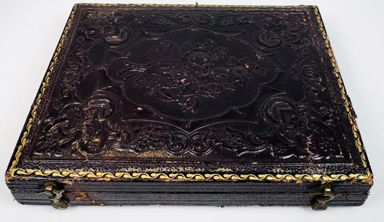 Antique photographic case with ornate embossed exterior, gilt border detailing, and metal closure hardware