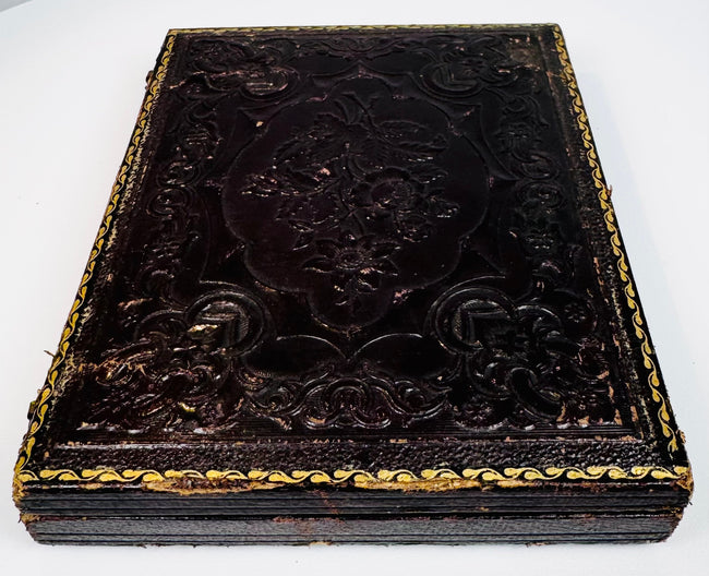 Closed mid-19th-century ambrotype case with deeply embossed floral and scroll decoration
