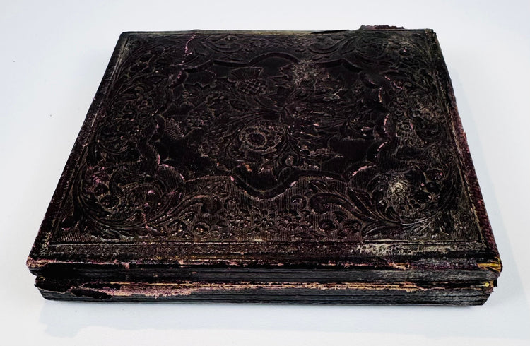 Antique cased photograph with ornate dark embossed exterior, decorative border, and age-related patina