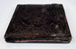 Antique cased photograph with ornate dark embossed exterior, decorative border, and age-related patina