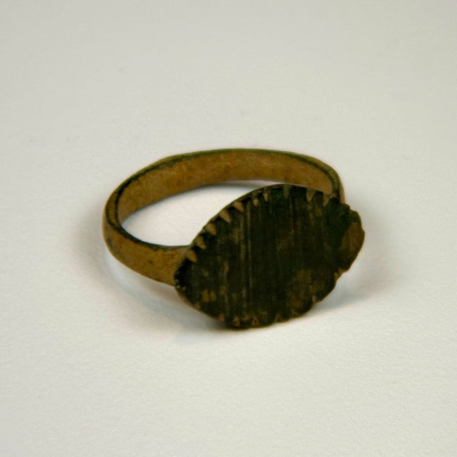 Roman period bronze ring featuring a substantial cast hoop and weathered engraved bezel
