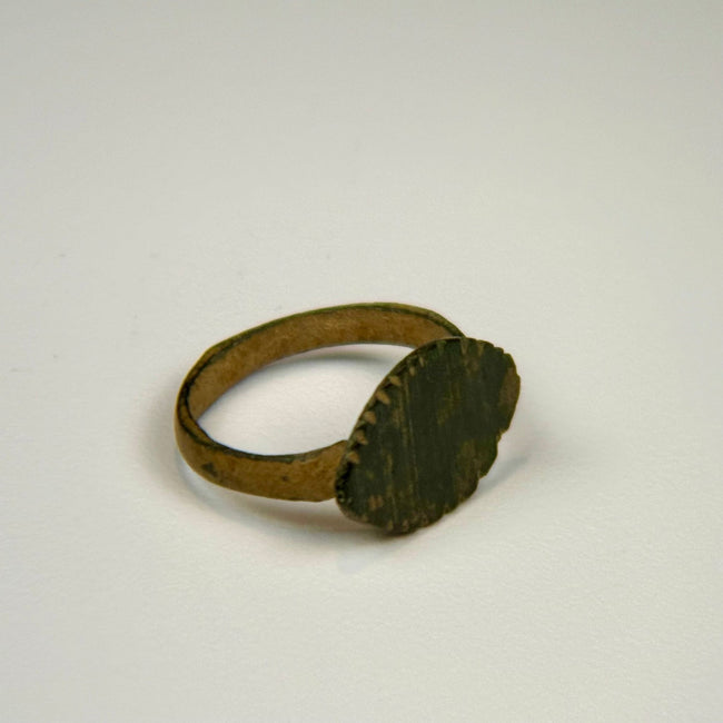 Ancient Roman bronze ring with gently curved band and incised geometric lines across the oval bezel