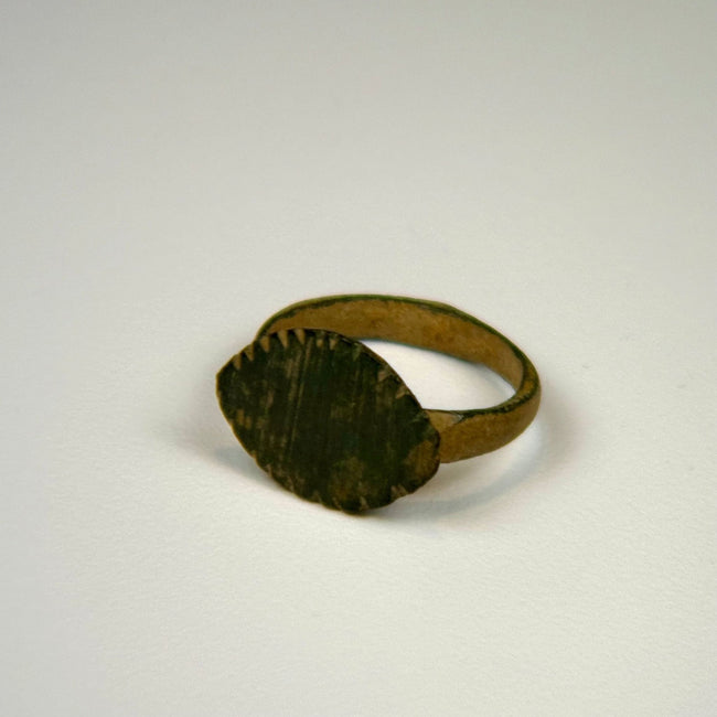 Roman bronze ring with prominent oval bezel, weathered surface, and traces of earthen encrustation