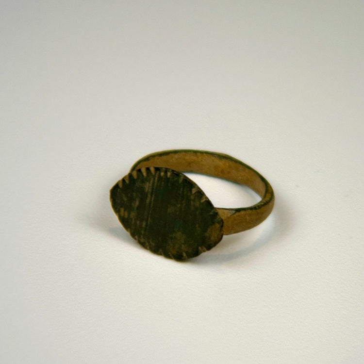 Roman bronze ring with prominent oval bezel, weathered surface, and traces of earthen encrustation