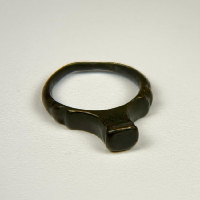 Ancient Roman bronze signet ring with broad flat bezel and deep green-black patina, circa 100–300 CE