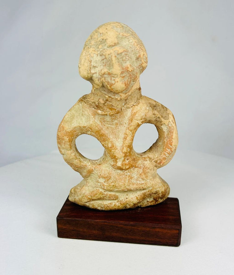 Mauryan terracotta figurine, circa 322–185 BCE, depicting a seated boy with arms bowed outward, traces of pigment, and natural aged patina.